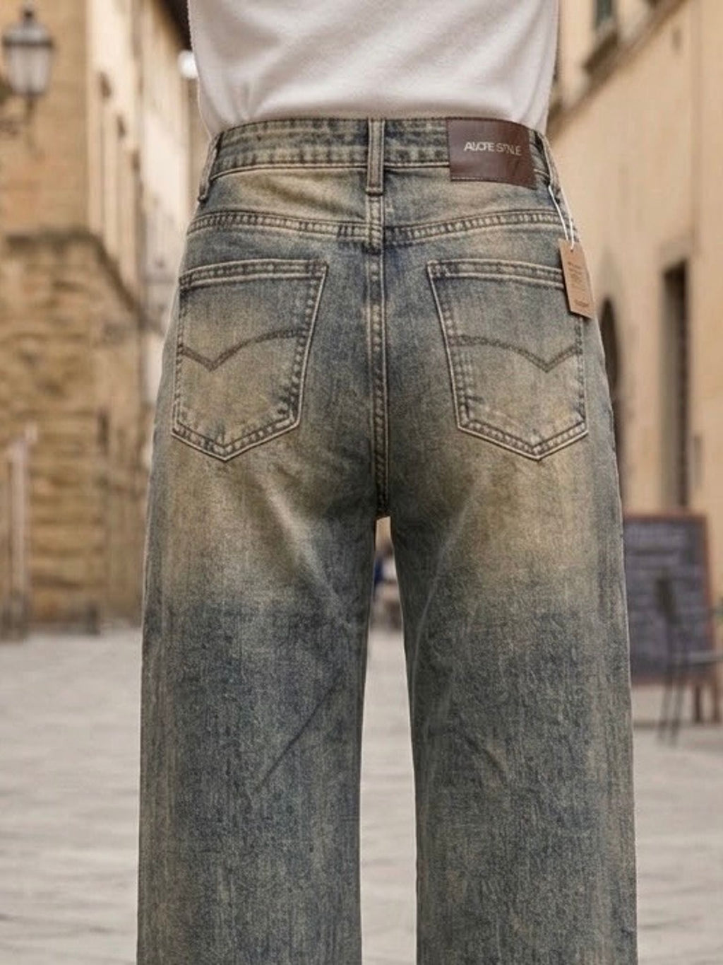 ⁠Dettaglio delle tasche posteriori e del lavaggio vintage sfumato di jeans a palazzo elasticizzati.