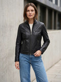 ⁠Giacca da donna in vera pelle nappa nera Made in Italy con collo alla coreana, chiusura zip a vista e quattro tasche con cerniera, indossata con jeans