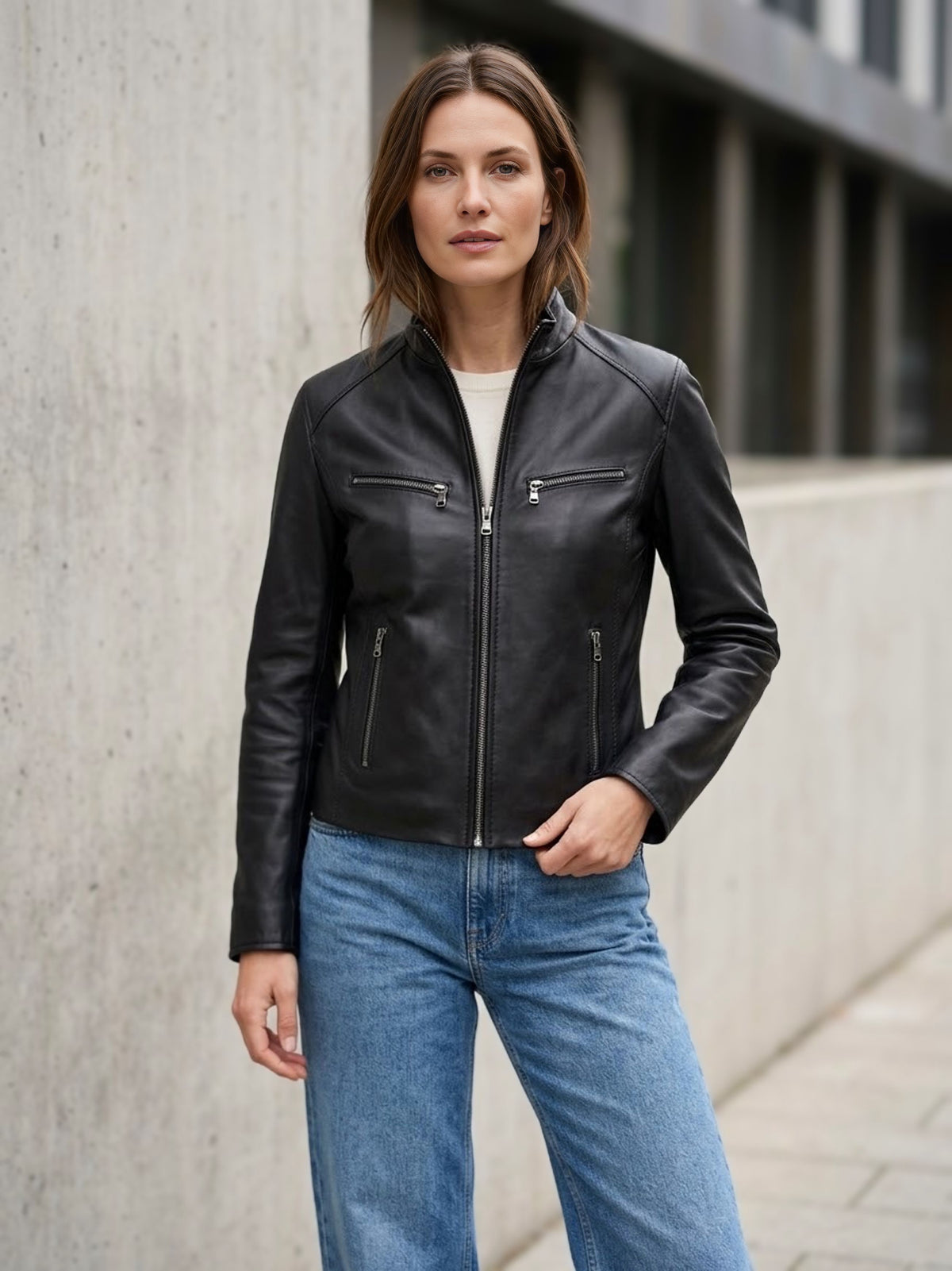 ⁠Giacca da donna in vera pelle nappa nera Made in Italy con collo alla coreana, chiusura zip a vista e quattro tasche con cerniera, indossata con jeans