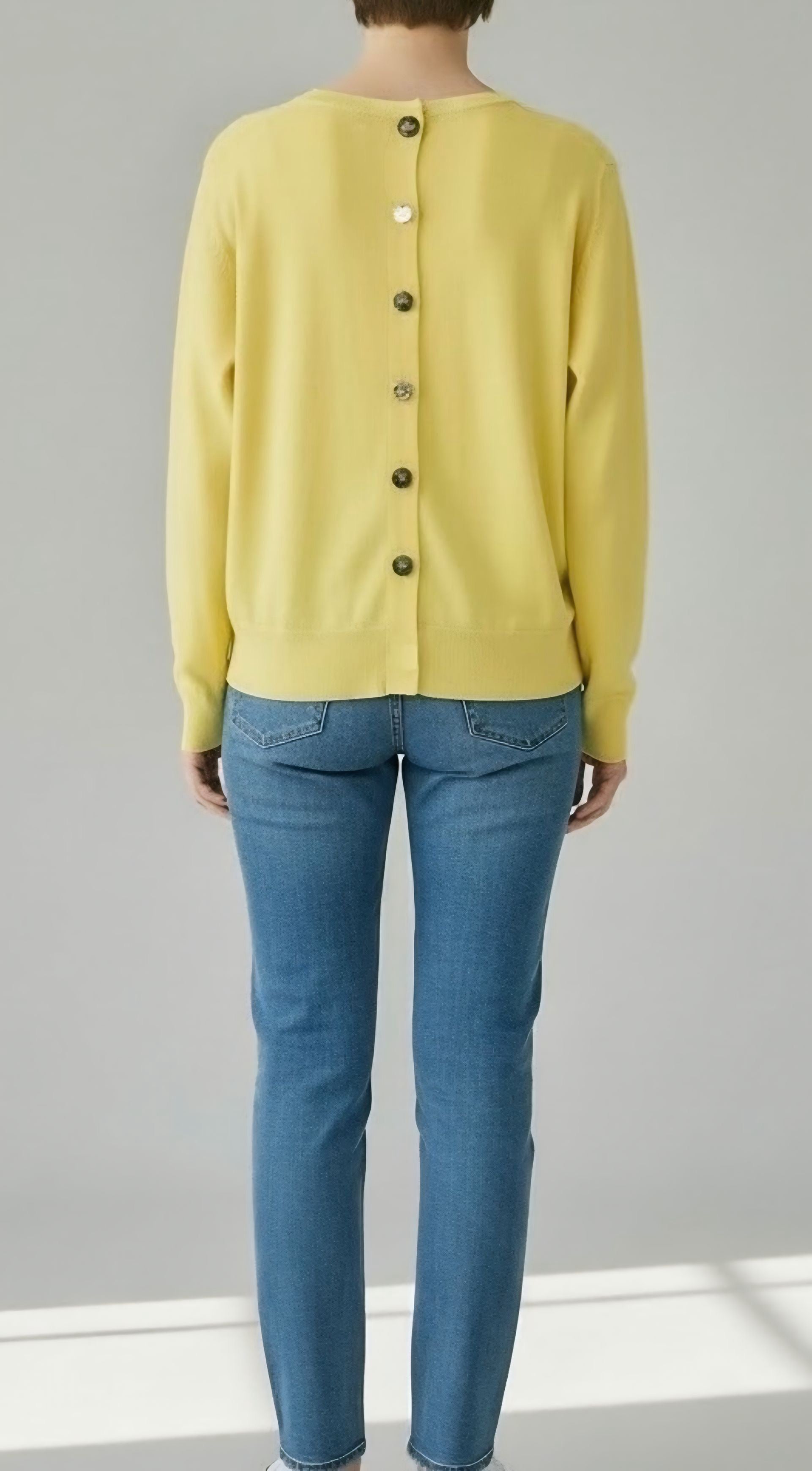 Dettaglio retro di una maglia leggera da donna, chiusura con fila di bottoni dorati eleganti