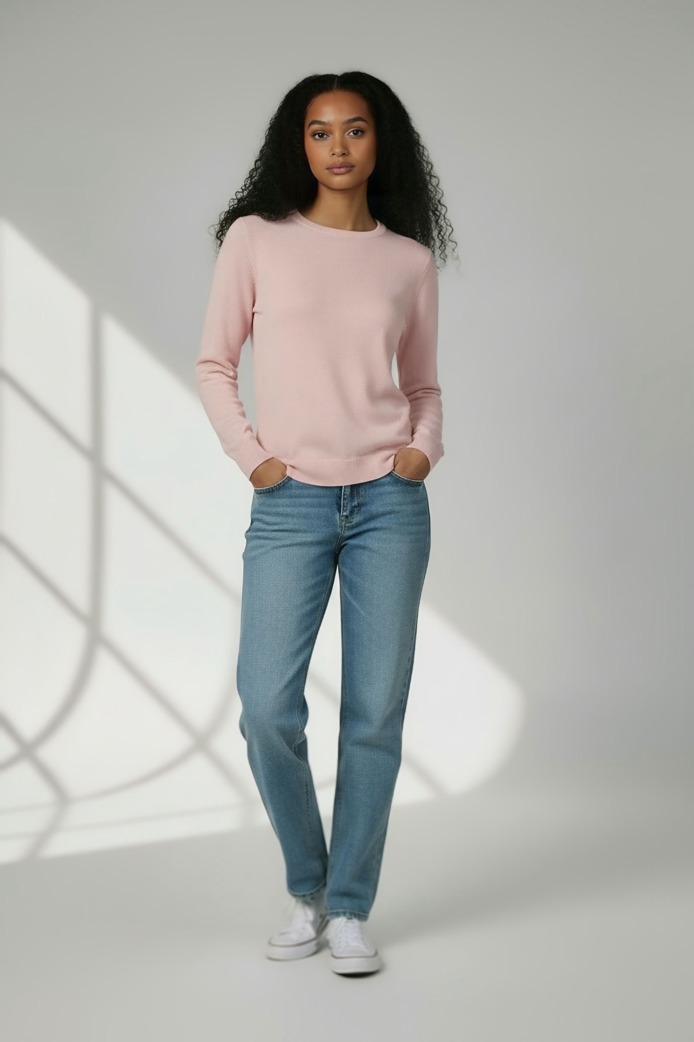 Donna indossa maglia rosa pastello a maniche lunghe in tessuto ultra-leggero, stile minimalista abbinata a jeans, collezione primavera-estate - centro della pelle.