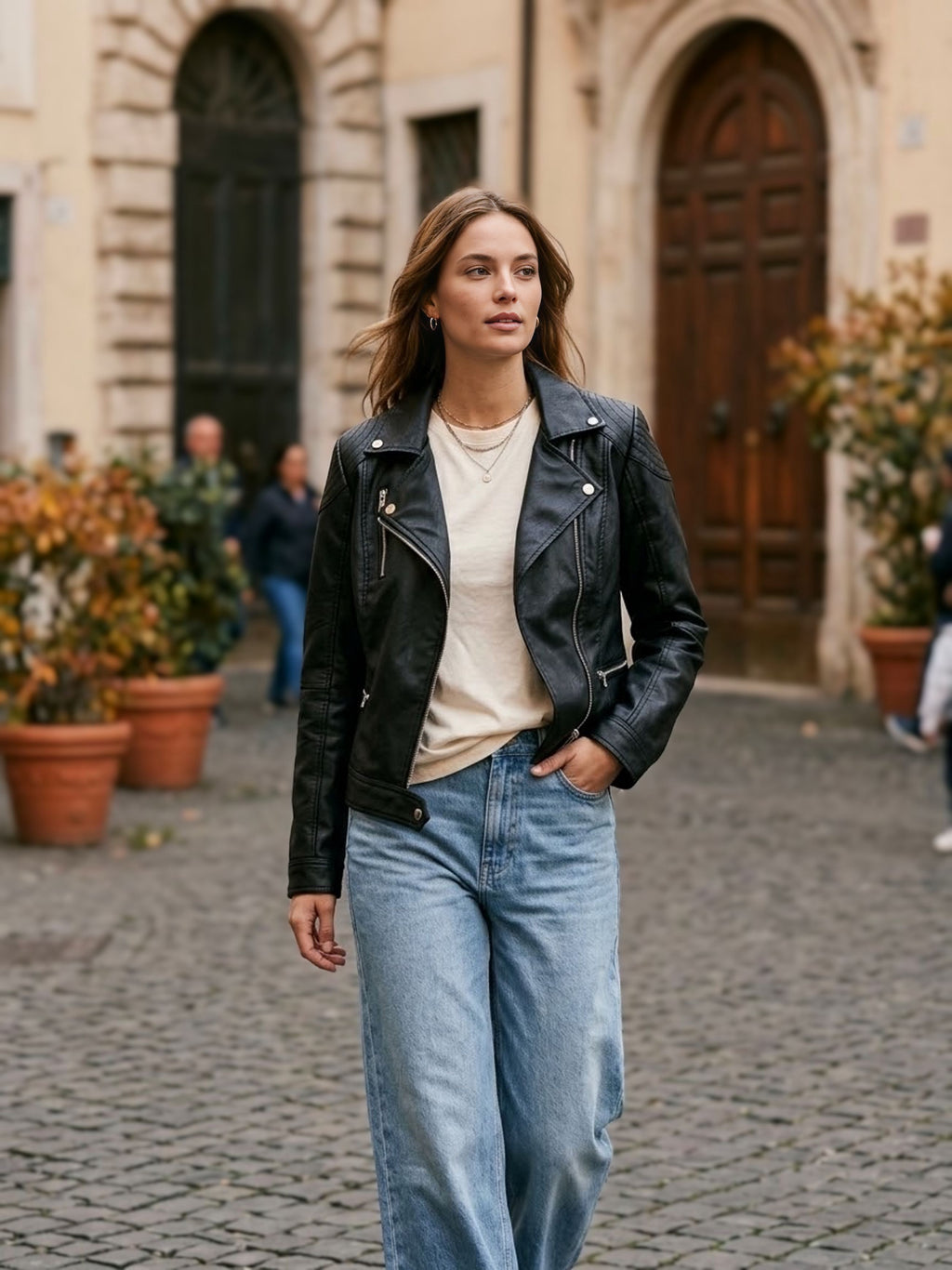 ⁠Giacca chiodo in ecopelle nera da donna con zip asimmetrica argento e dettagli trapuntati sulle spalle, vista frontale con outfit