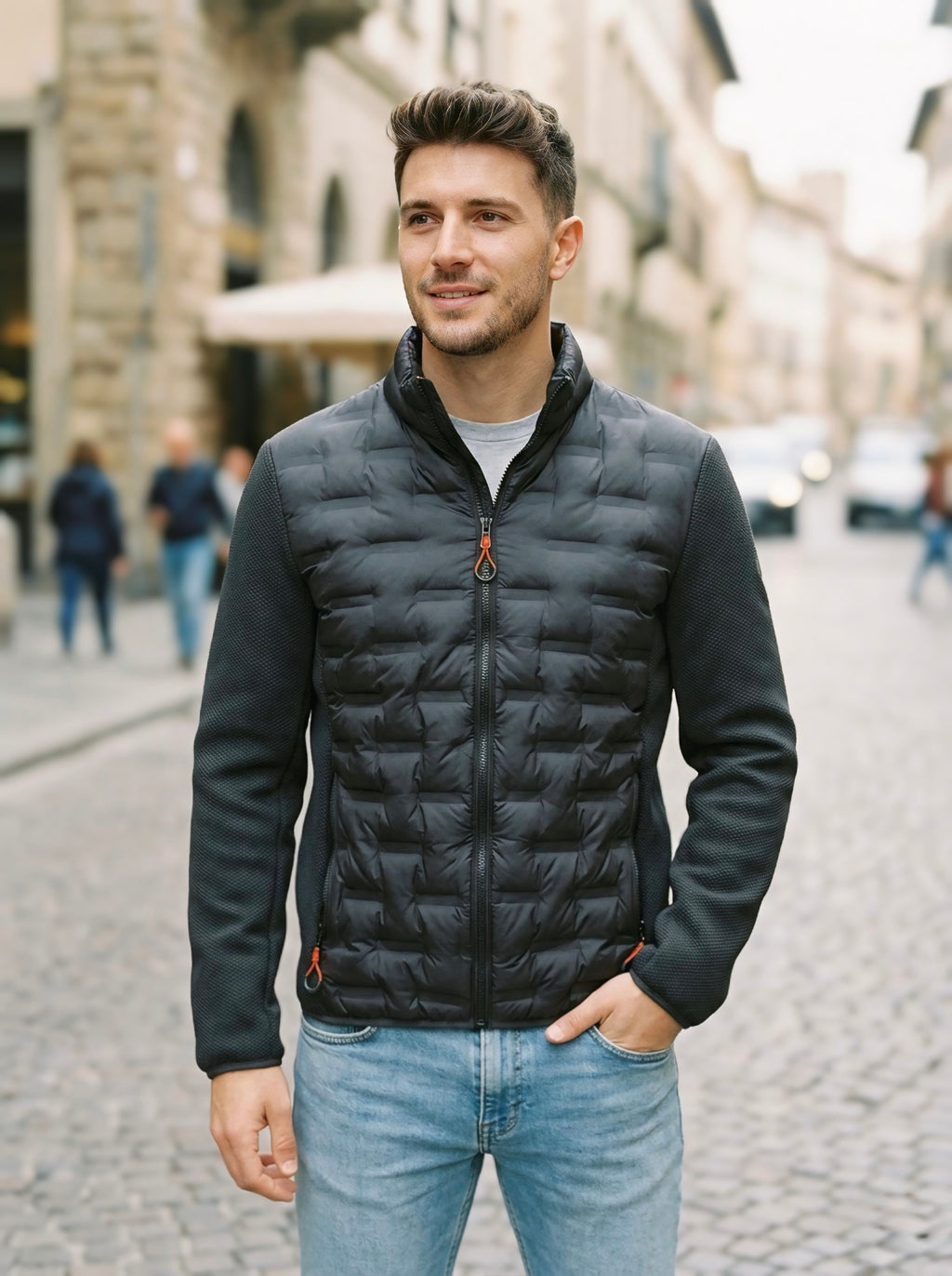 Giacca ibrida uomo nera con busto in eco-piuma termopressata e maniche in tessuto tecnico, vestibilità slim, chiusura con zip colorata.